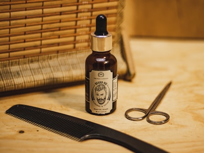 Close-up of grooming products like beard oil, combs, and scissors arranged neatly on a wooden counter.