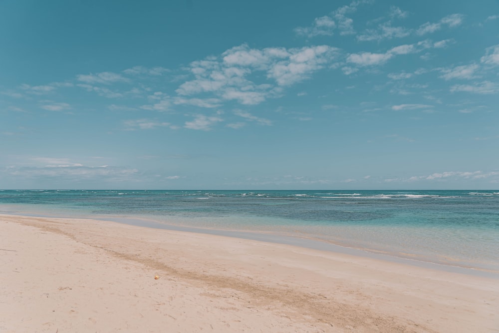 a sandy beach with clear blue water under a blue sky