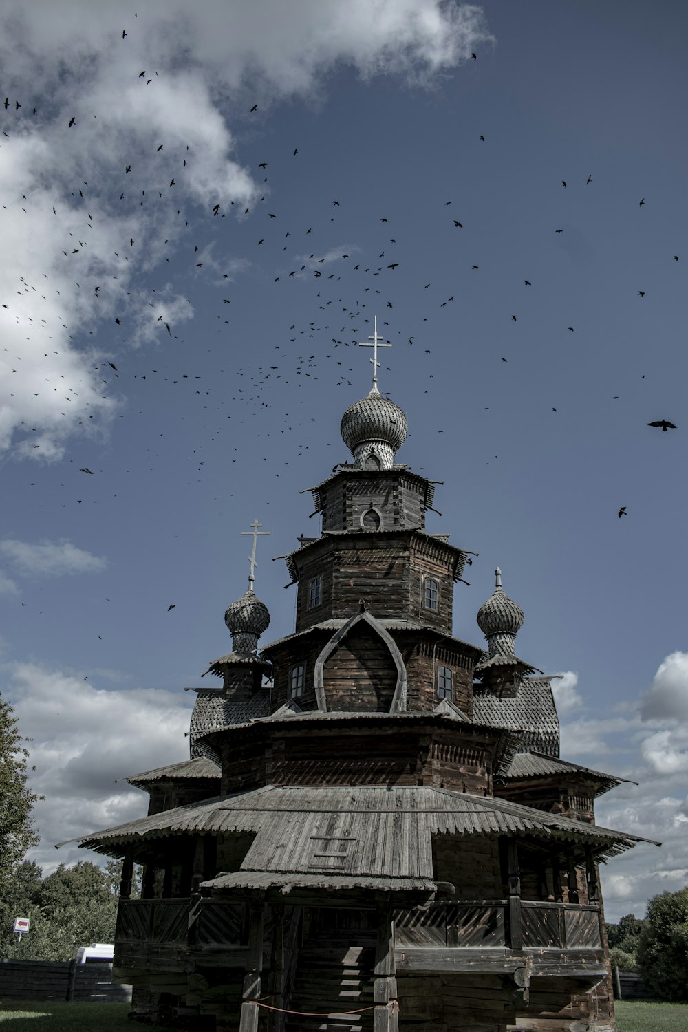 a large wooden building with many birds flying around it