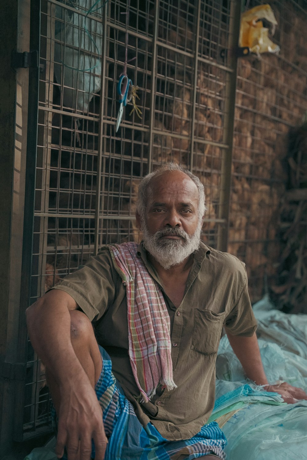 a man sitting on a bed next to a cage