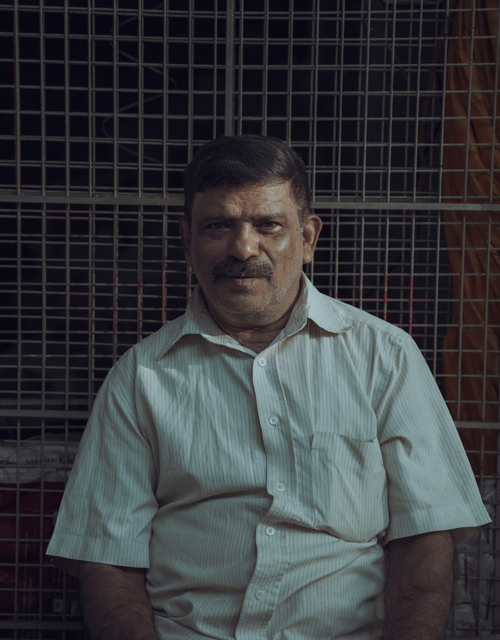 a man sitting in front of a metal cage