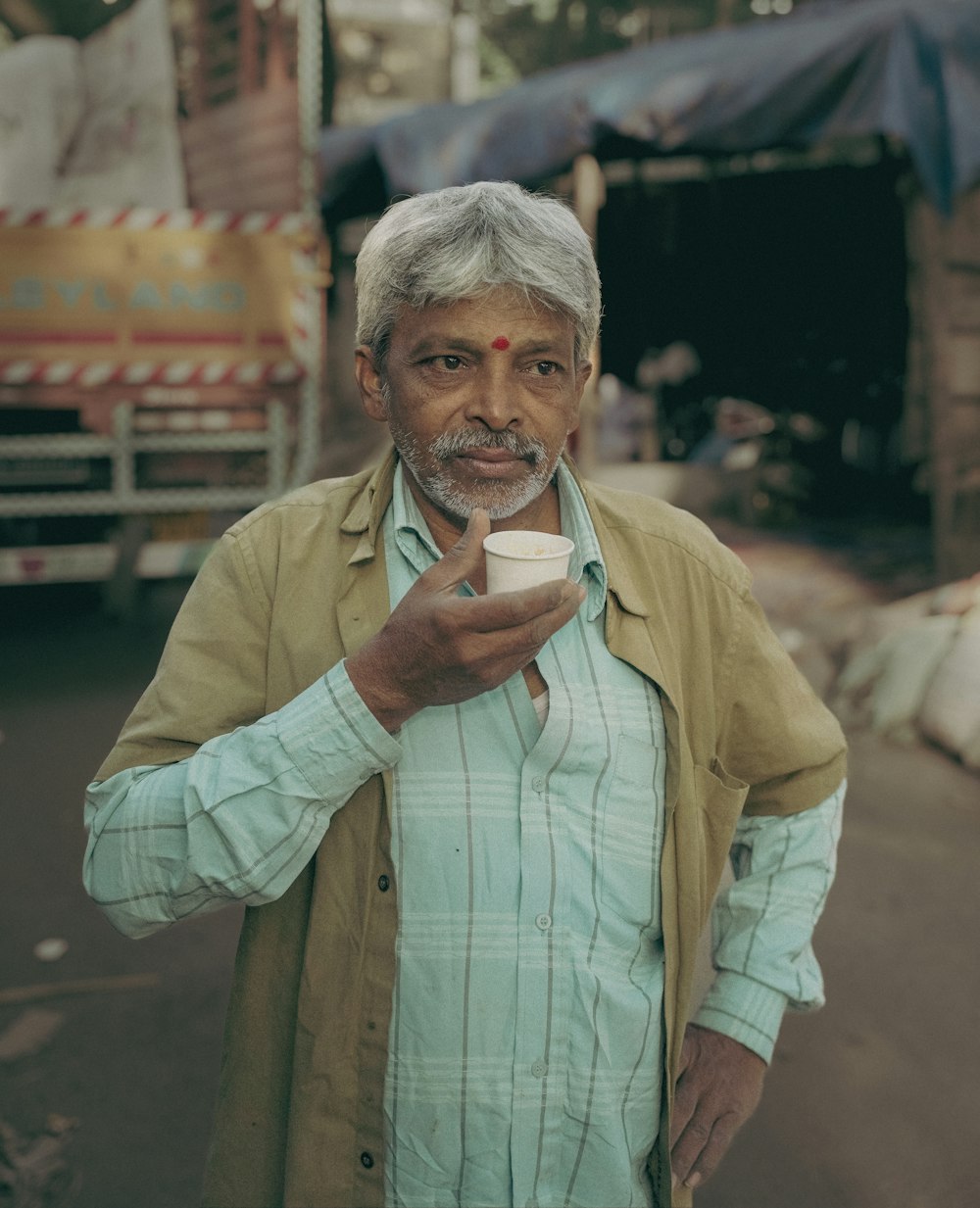un homme debout dans une rue tenant une tasse de café