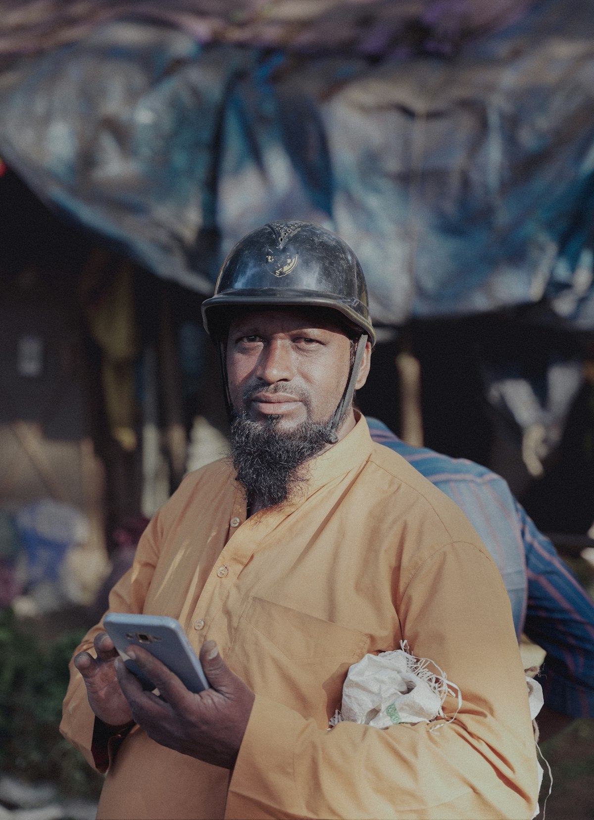 Contractor in a hard hat checking his phone at a job site while weighing jobber alternatives