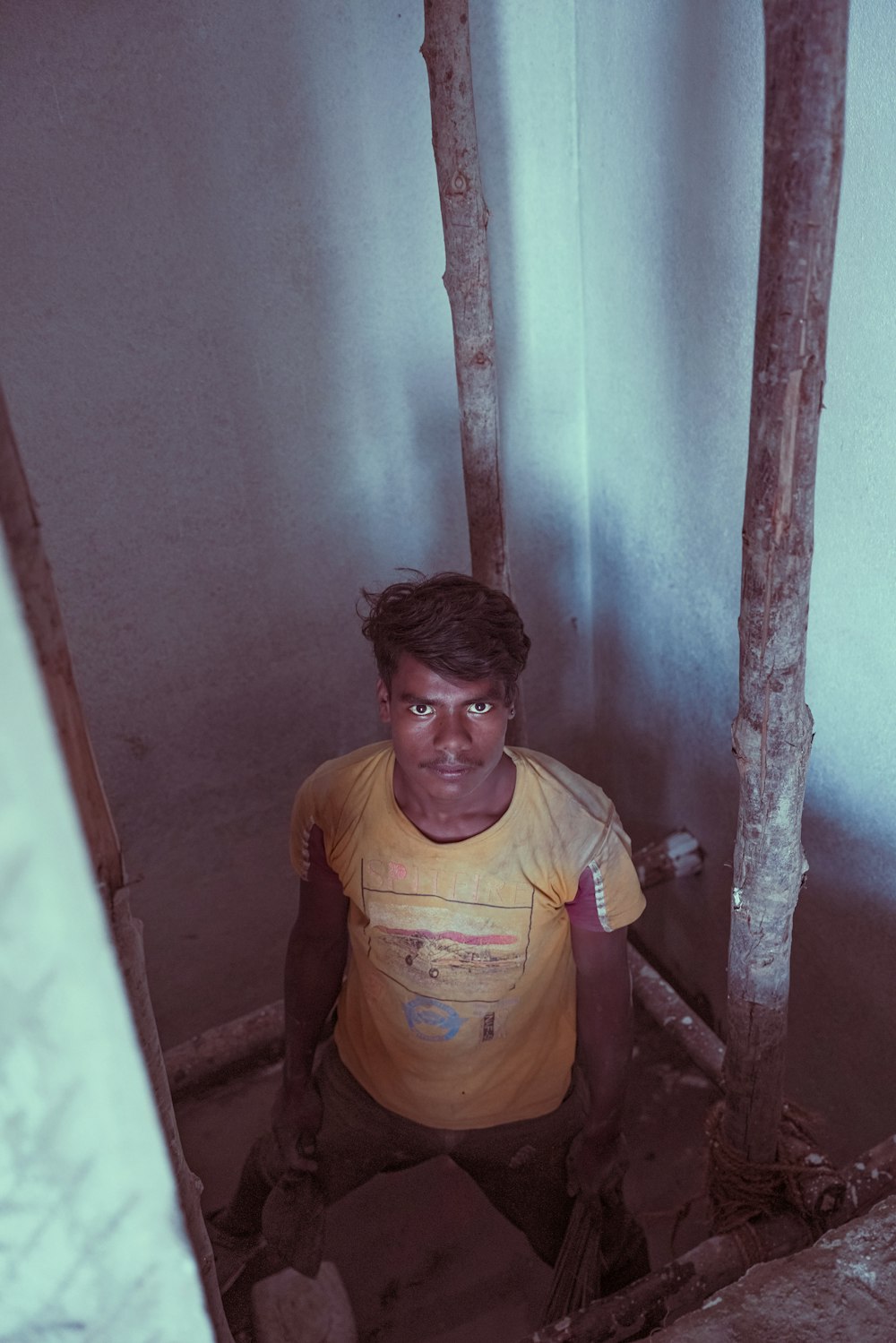 a young man sitting in a corner of a room