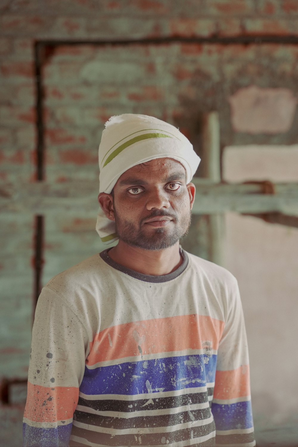 a man with a turban standing in front of a brick wall