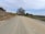 A well-graded gravel road lined with trees under a clear sky.