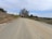 A well-graded gravel road lined with trees under a clear sky.