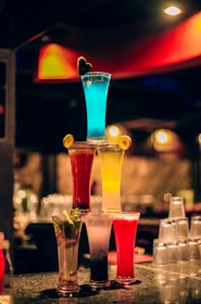 A collection of colorful cocktail glasses on a wooden bar.