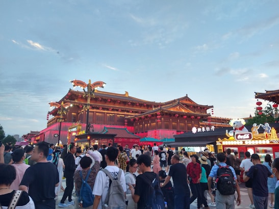A lively crowd sampling dishes at a bustling Chinese culinary event under red lanterns.