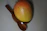 Close-up of a ripe, golden Multani mango resting on a rustic wooden table.