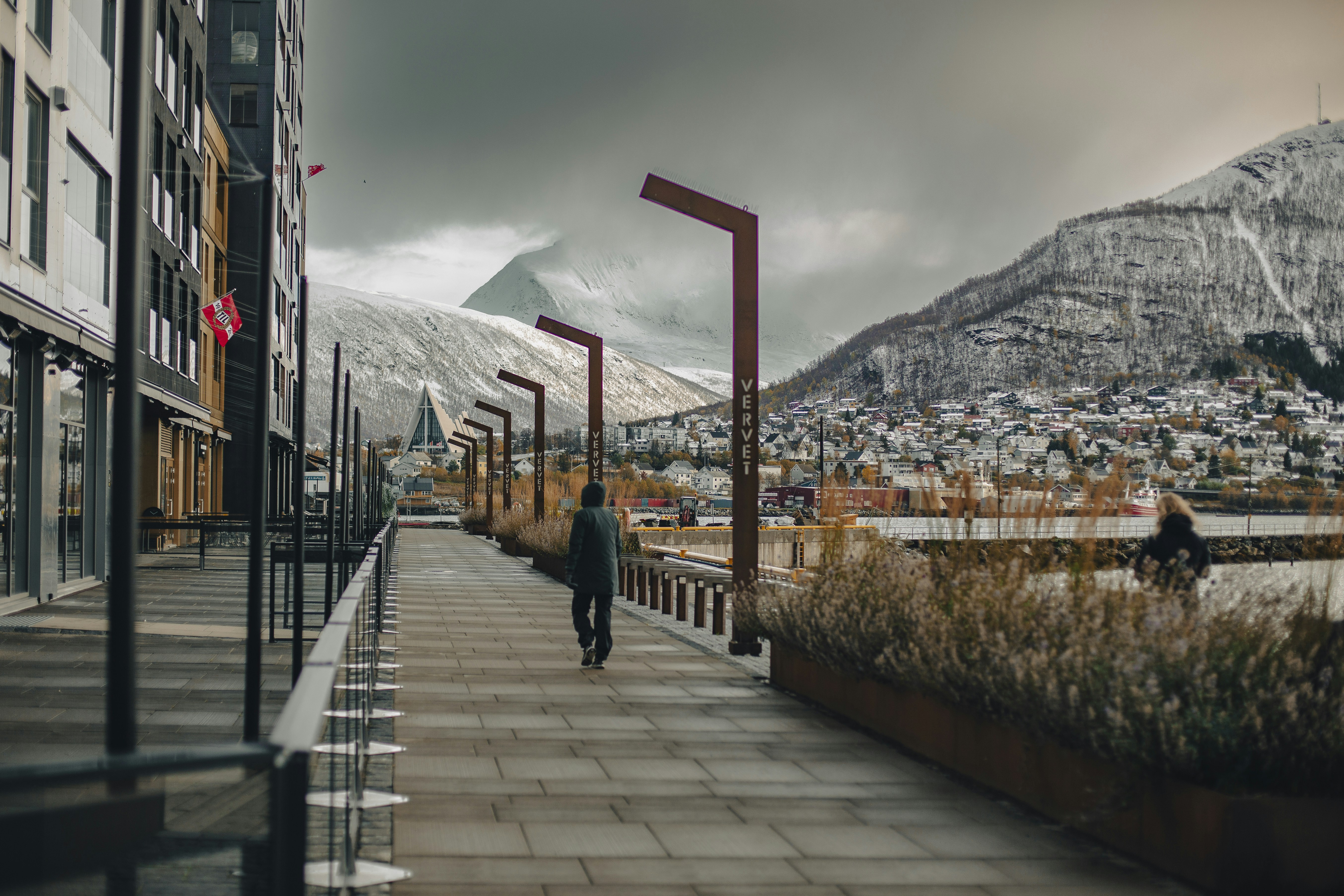 a man walking down a sidewalk next to a tall building