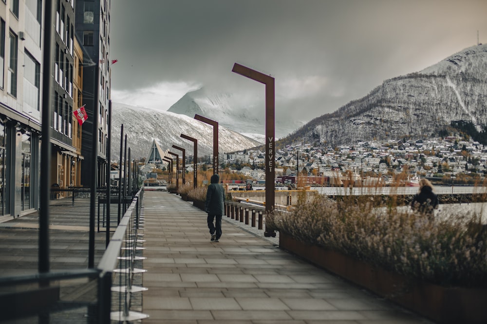 a man walking down a sidewalk next to a tall building