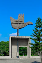 a sculpture of a hand holding a tree in front of a building
