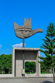 a sculpture of a hand holding a tree in front of a building