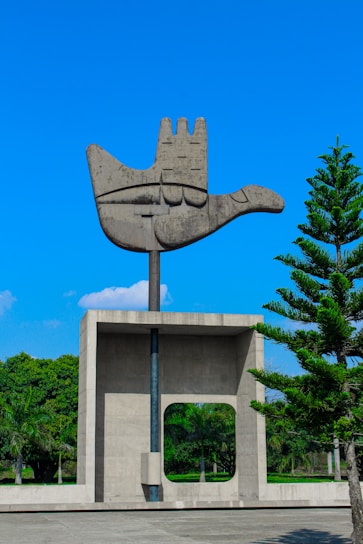 a sculpture of a hand holding a tree in front of a building