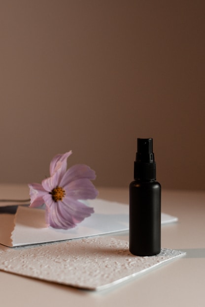 a bottle of perfume sitting on top of a table next to a flower
