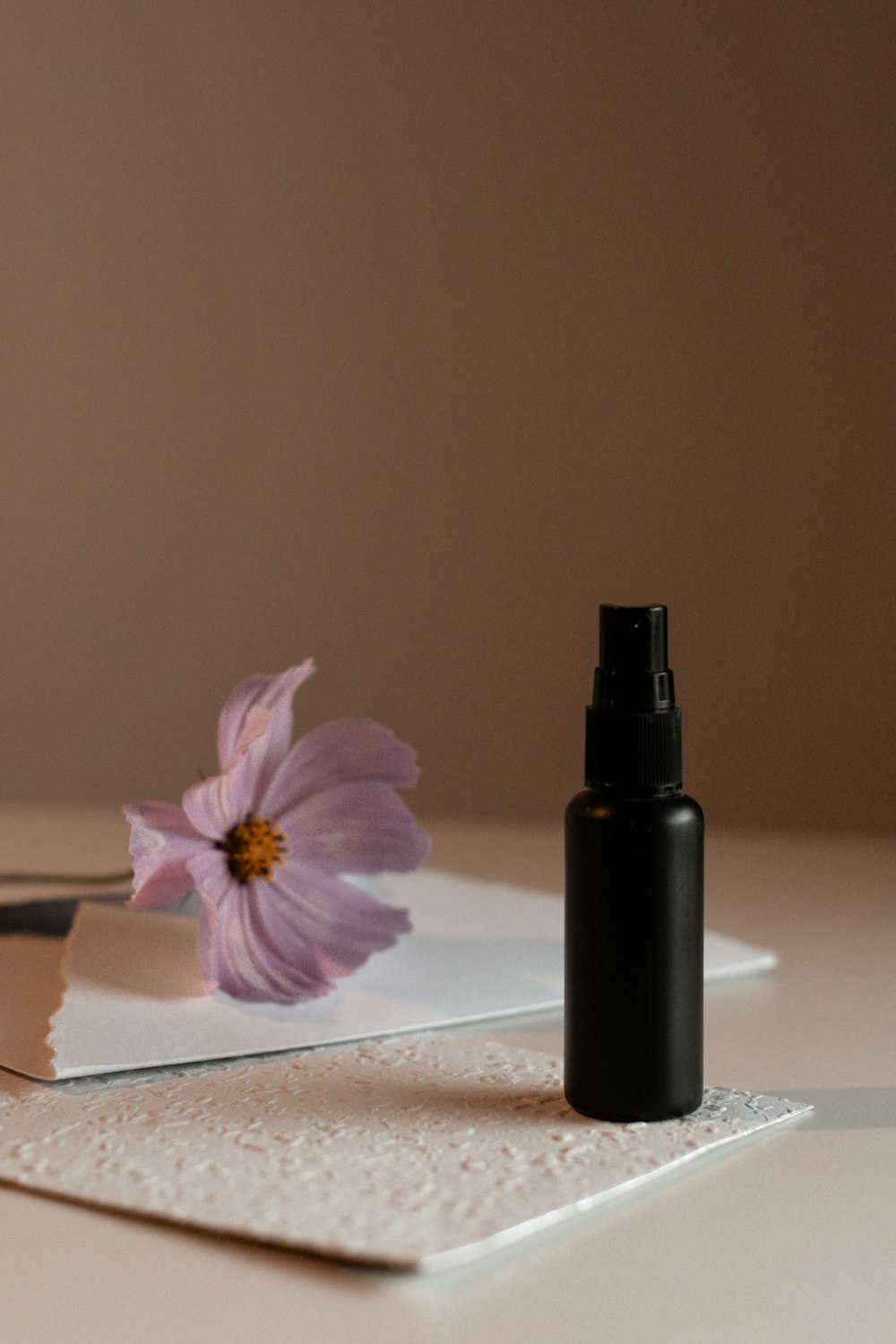 a bottle of perfume sitting on top of a table next to a flower
