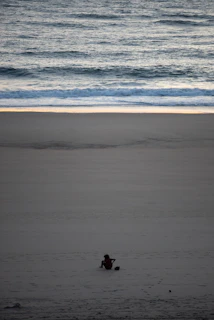 A solo traveler relaxing on a sandy beach, soaking in the peaceful ocean breeze and golden sunlight.