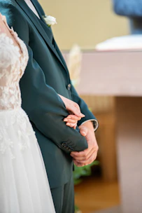 A close-up of a couple holding hands during a private anniversary celebration in a secluded garden.