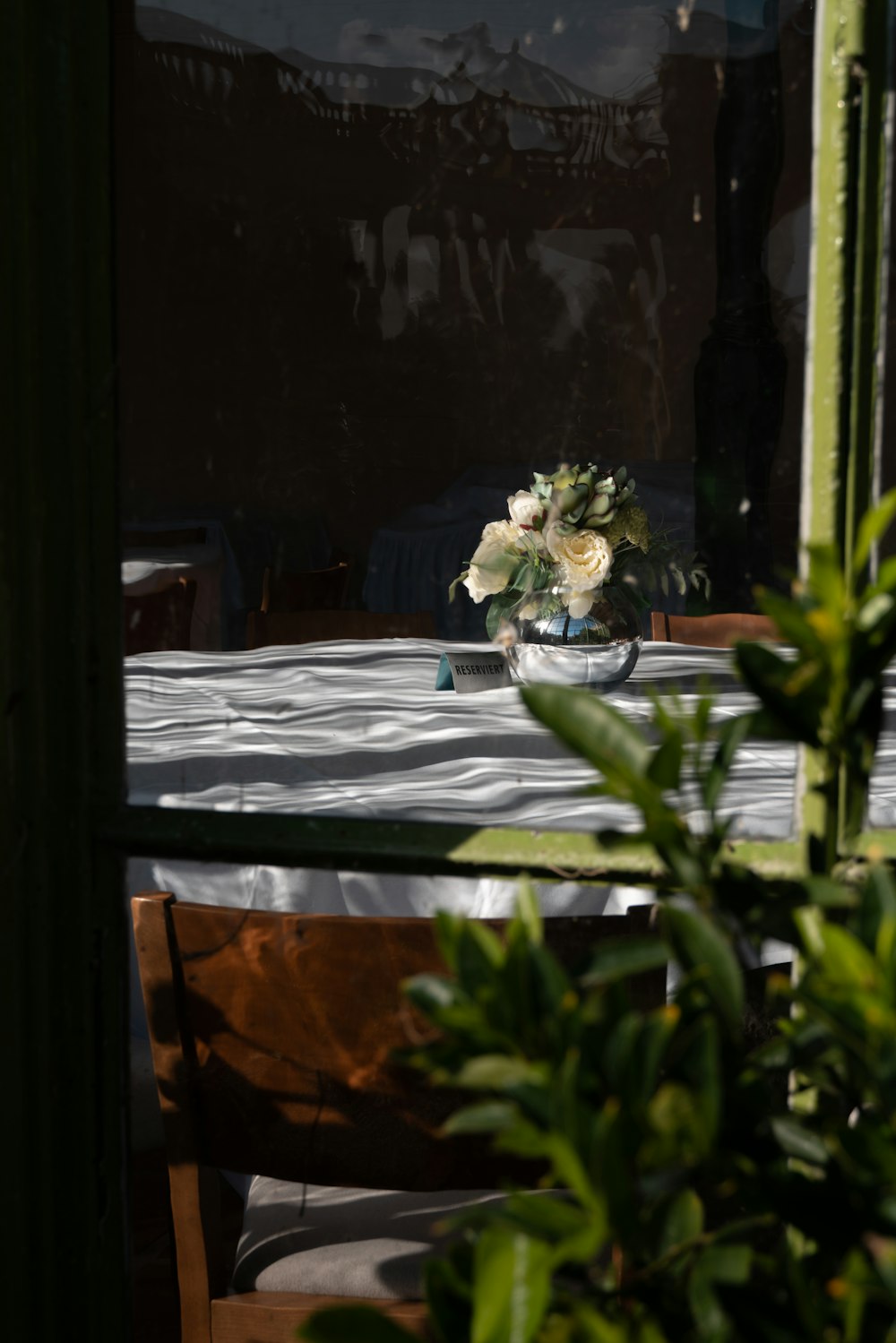 eine Vase mit Blumen, die auf einem Tisch vor einem Fenster steht