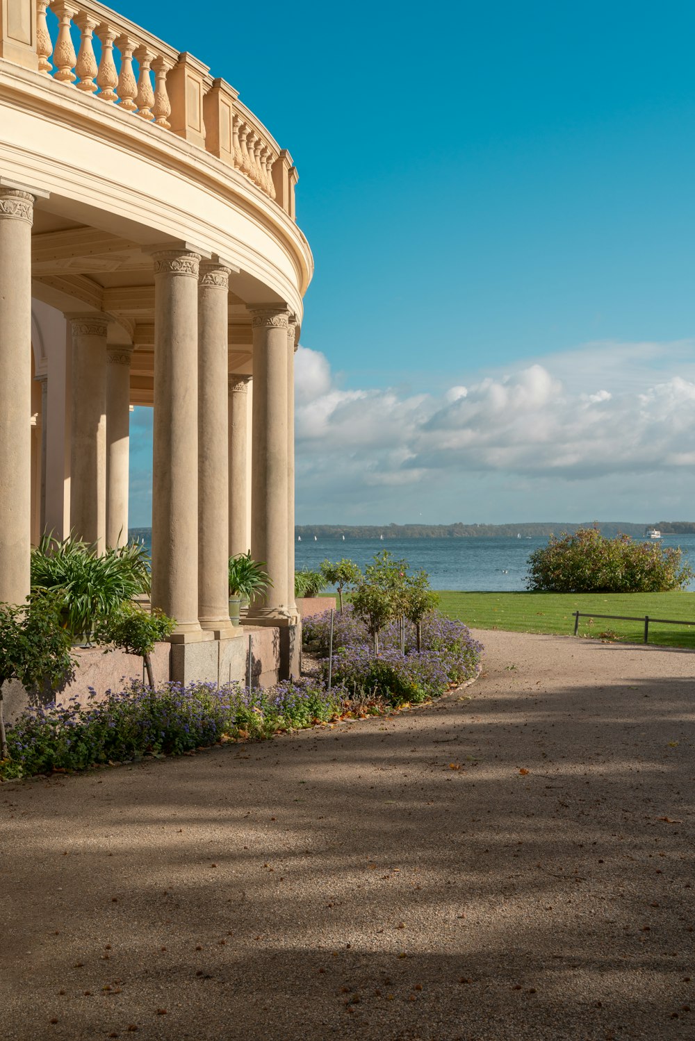 a view of a building with columns and flowers in the foreground