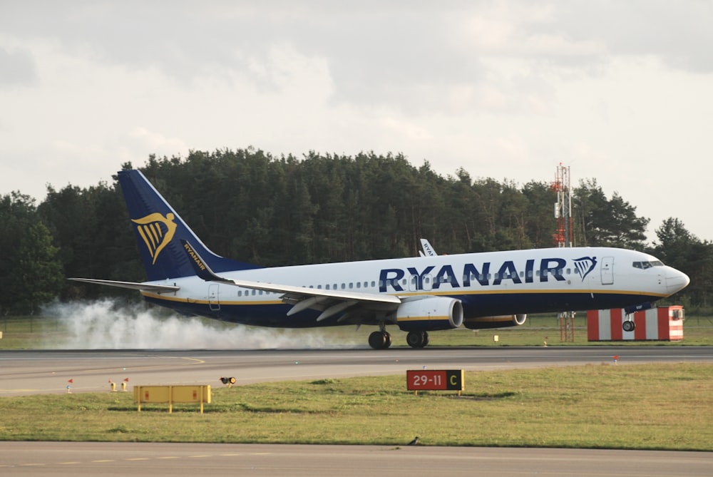 a blue and white jet airliner taking off from an airport runway