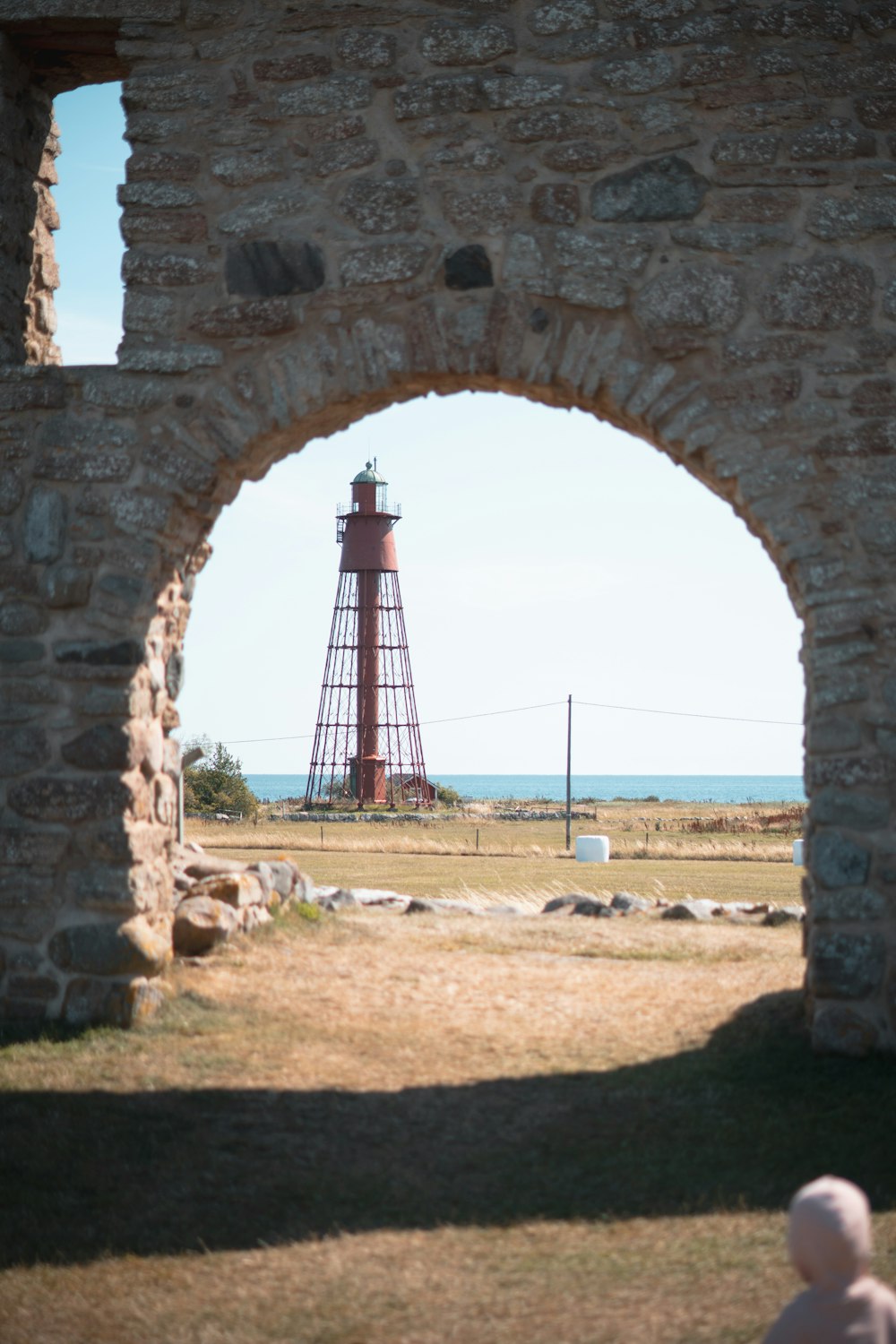 a lighthouse is seen through an arch in a stone wall