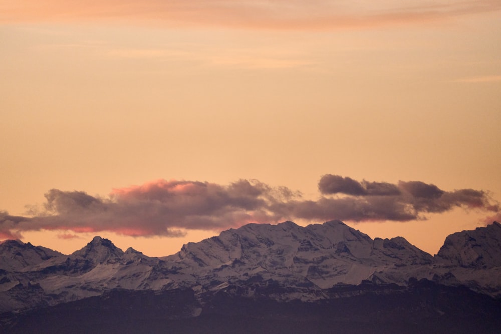 a plane flying over a mountain range at sunset