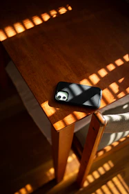 A sleek smartphone resting on a wooden table with soft natural light.