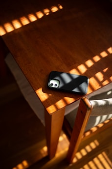 A sleek smartphone resting on a wooden table with a soft natural light.