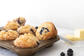 Freshly baked muffins with blueberries peeking through the tops.