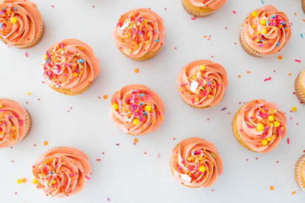 a table topped with lots of cupcakes covered in frosting