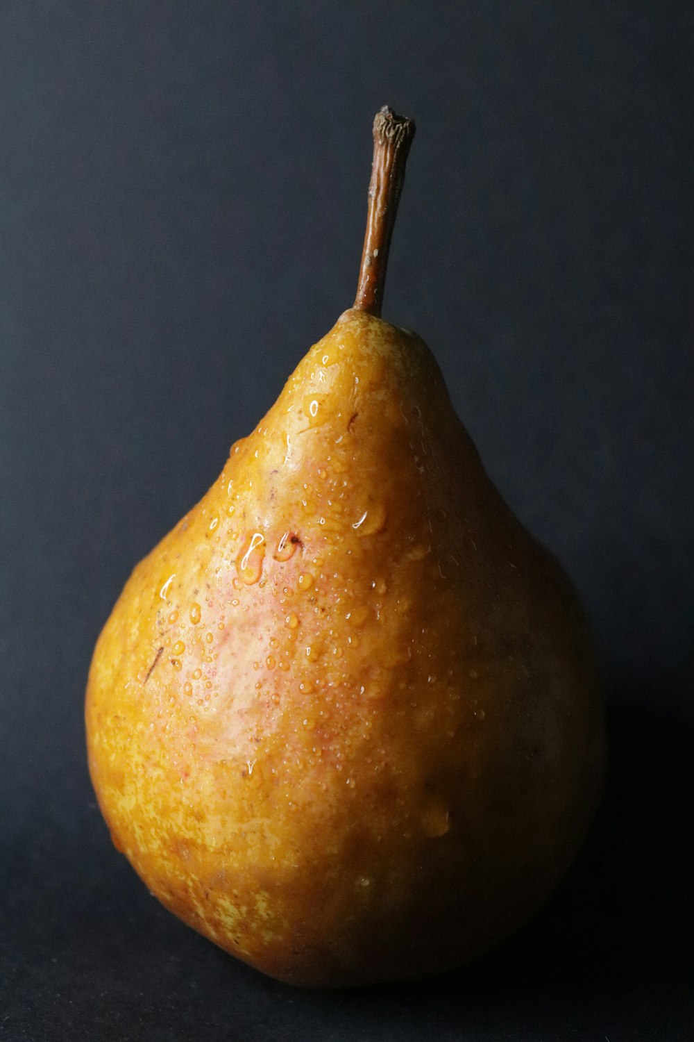a pear with a brown stem on a black surface