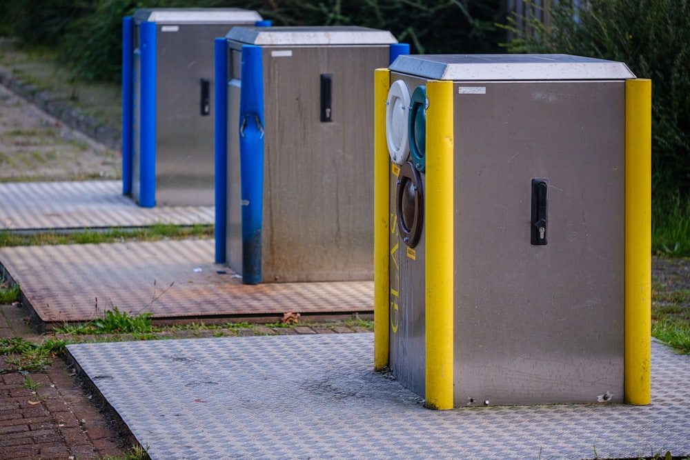 a row of metal trash cans sitting on top of a sidewalk