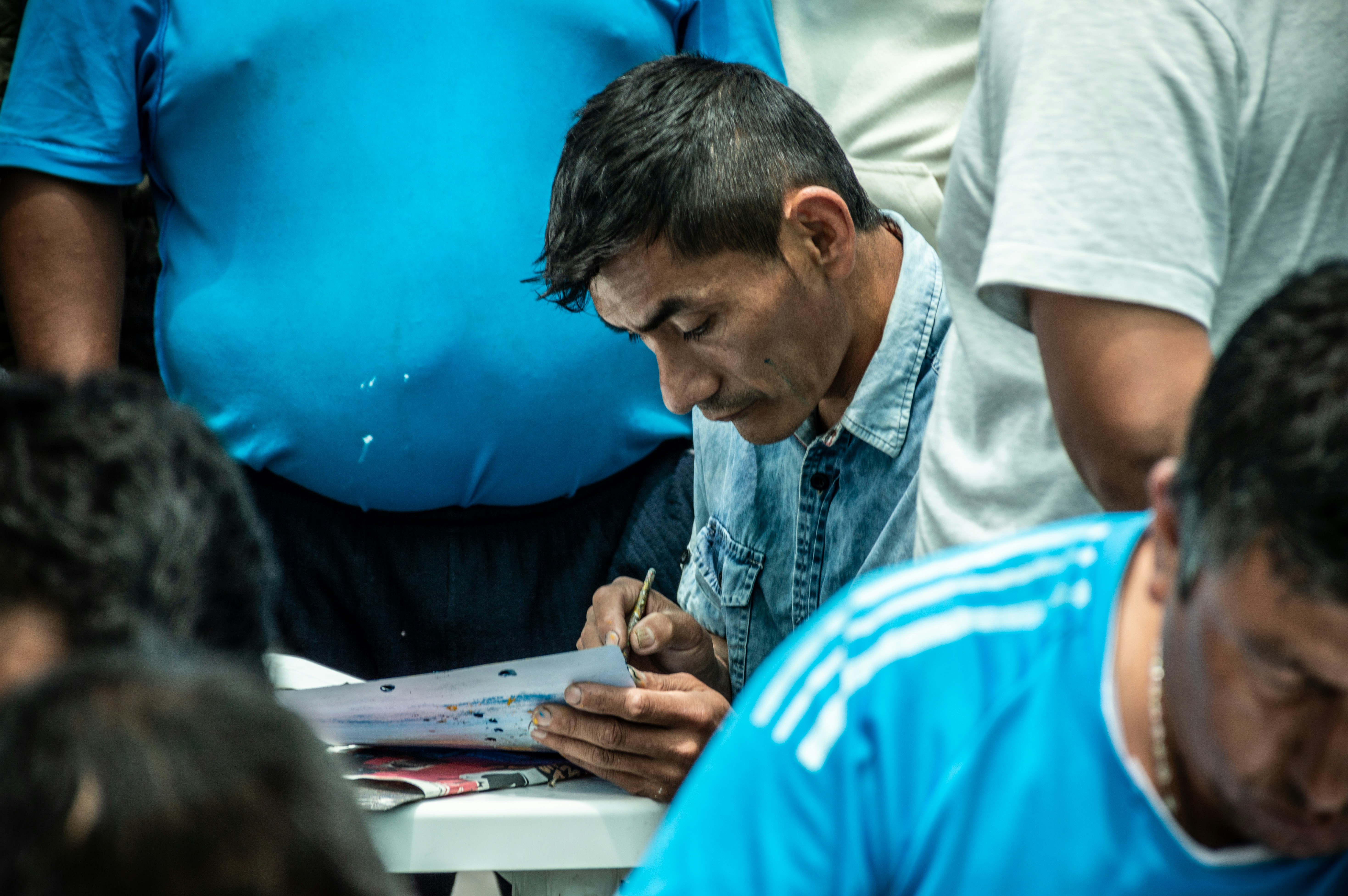 a man sitting at a table writing on a piece of paper