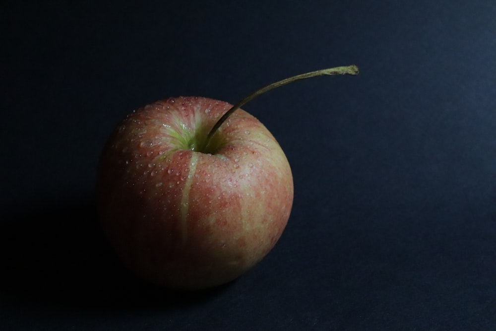 a red apple sitting on top of a black table