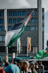 A vibrant group of Nigerian youths waving green and white flags, standing together in front of a city skyline.