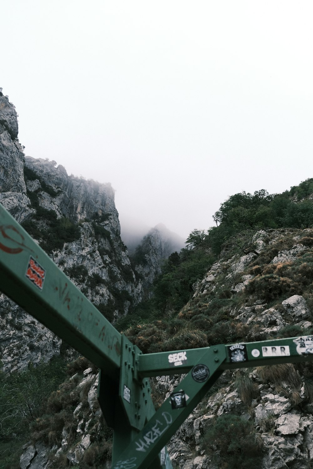 a green metal bridge with a mountain in the background
