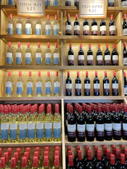 Bottles of blueberry wine lined up on a rustic wooden shelf in the winery.