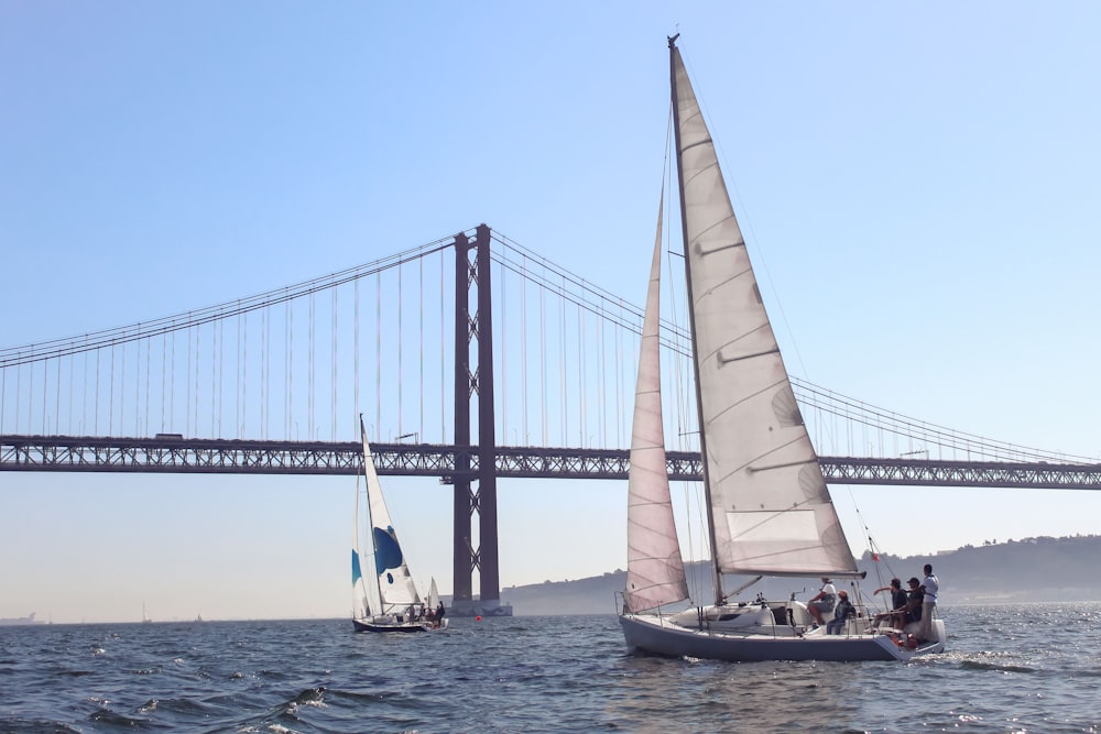 a sailboat sailing under a bridge on the water