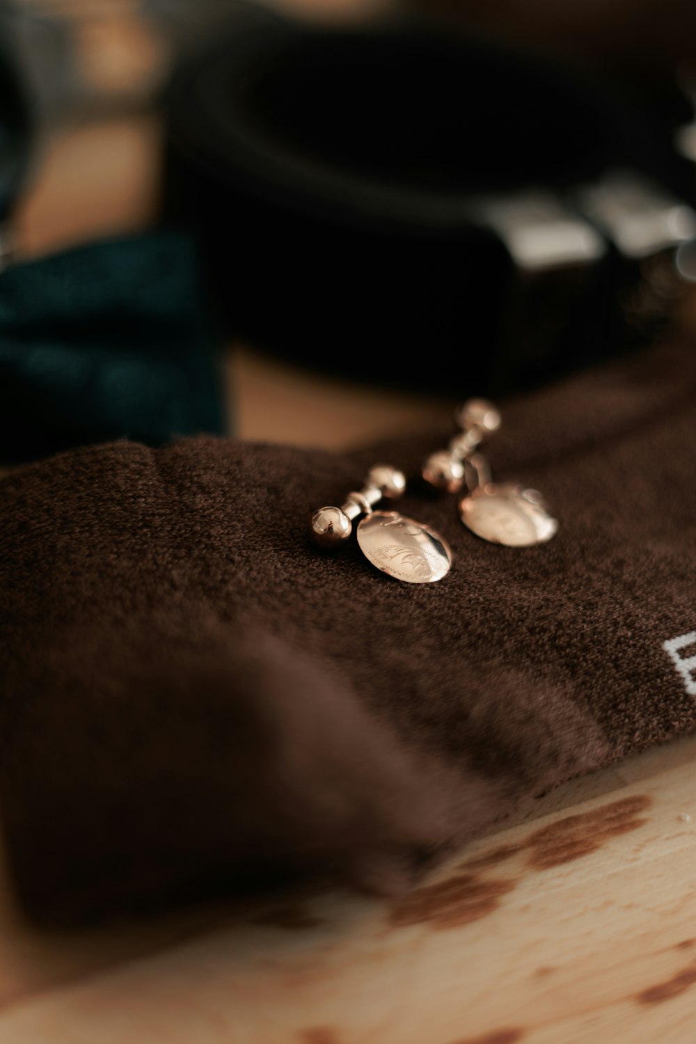 a pair of earrings sitting on top of a brown cloth