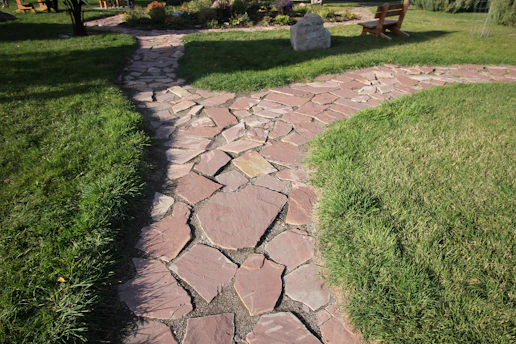 A freshly installed interlocking stone pathway winding through a vibrant Ottawa garden.