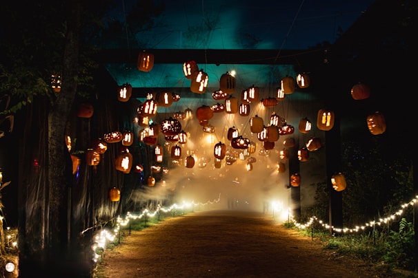 Children laughing as they walk along the haunted path lined with whimsical pumpkins and soft glowing lanterns.