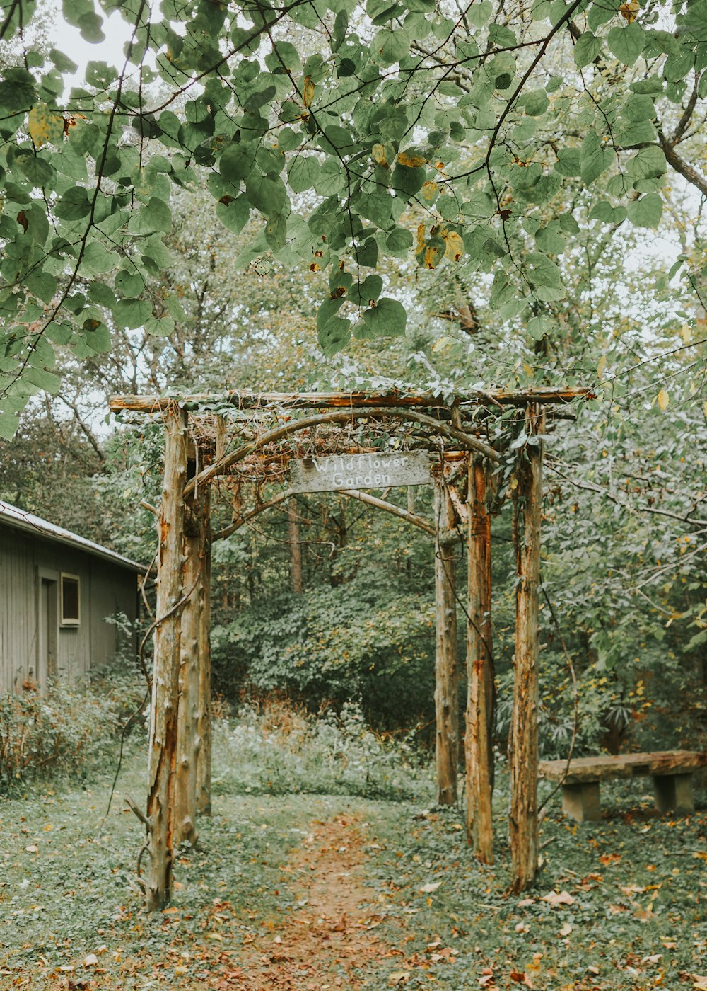 a wooden arbor in a yard with a house in the background