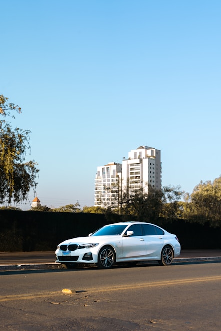 A sleek white sedan parked by a vibrant Bhubaneswar street with temples in the background.