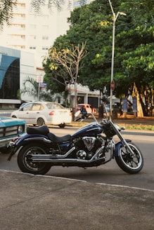 A sleek blue motorcycle parked on a city street at sunset.
