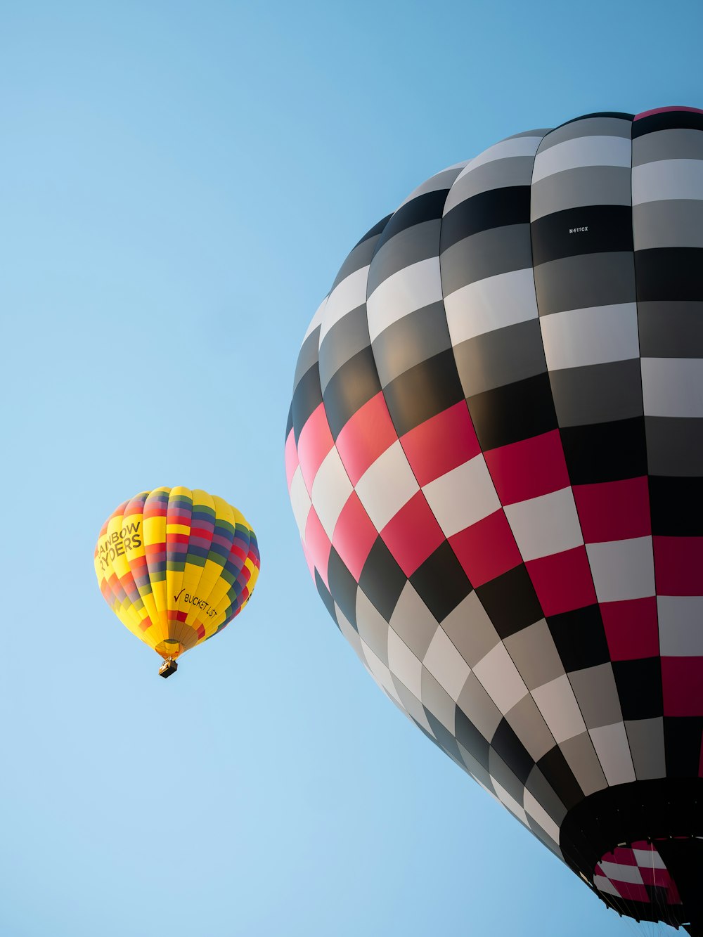 a couple of hot air balloons flying through a blue sky