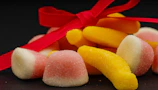 Close-up detail of a golden-accented candy bouquet tied with a delicate cream and pink ribbon