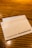 A wooden table surface with a white napkin featuring the Starbucks logo and text indicating the company's focus on sourcing and roasting coffee since 1971.