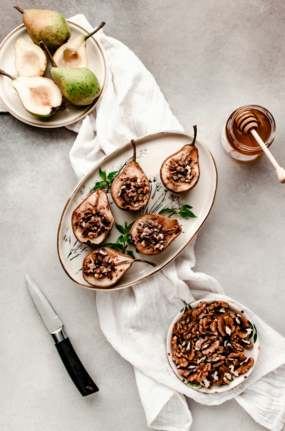 a white plate topped with sliced pears next to a bowl of nuts